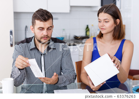 Upset young couple with bill and box having conflict at home Upset young couple with bill and box having conflict at home 63376263
