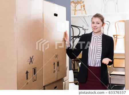 Confident woman among goods boxes in chair store 63376337