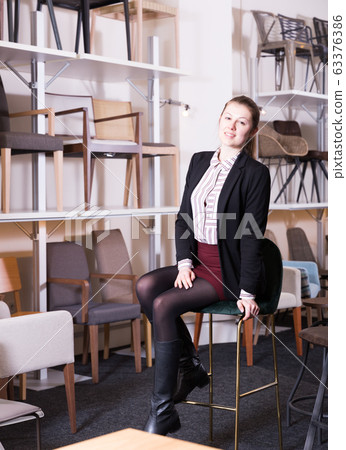 Female sitting on chair in furniture store 63376386