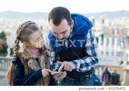 Father and daughter looking at guide in phone 63376452