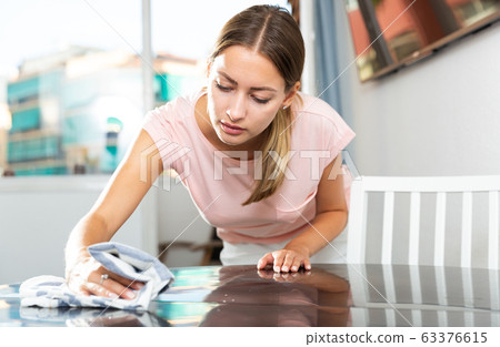 Girl with dishcloth cleaning kitchen table Girl with dishcloth cleaning kitchen table 63376615
