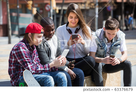 Teenage relaxing with mobile phones 63376679