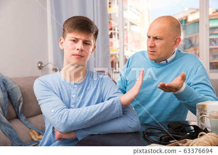 Father scolding his turned away son 63376694