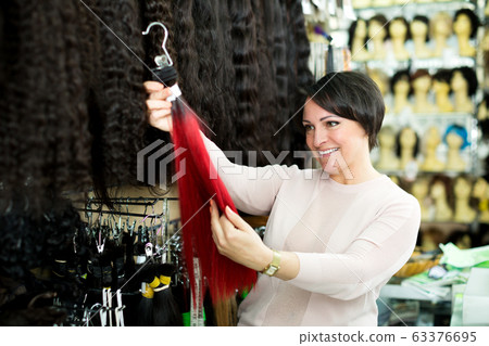 Smiling female customer selecting clip-in hair Smiling female customer selecting clip-in hair 63376695