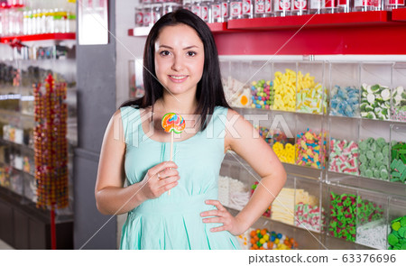Smiling girl sucking lollypop in store Smiling girl sucking lollypop in store 63376696
