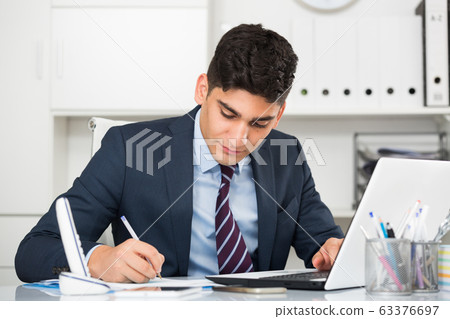 Adult man is working at a computer Adult man is working at a computer 63376697