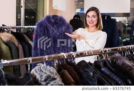 Adult woman choosing blue fur coat 63376745