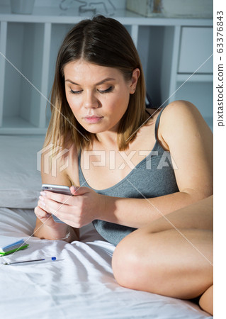 Sexy female is lying with smartphone on bed in bedroom 63376843