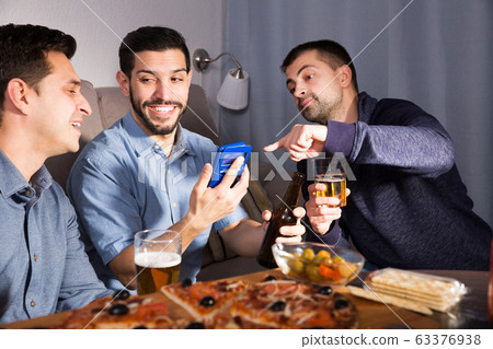 friends looking at phone while drinking beer friends looking at phone while drinking beer 63376938