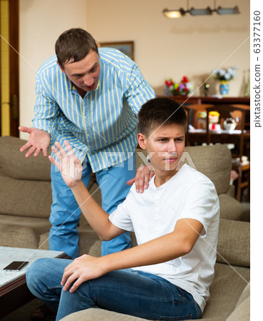 Man scolding his offended young son 63377160