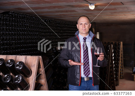 Winemaker offering red wine for tasting Winemaker offering red wine for tasting 63377163