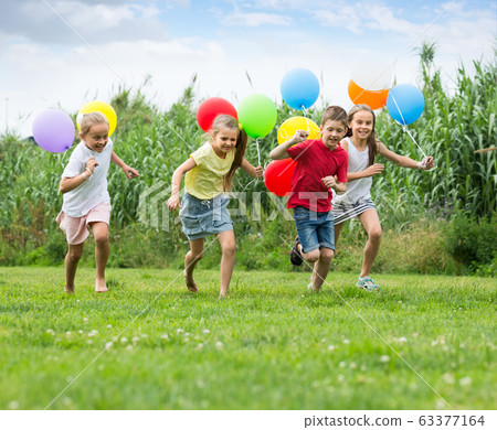 children running with air balloons in park . children running with air balloons in park . 63377164