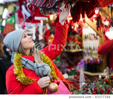 Positive smiling woman at fair near counter with Christmas gifts Positive smiling woman at fair near counter with Christmas gifts 63377168