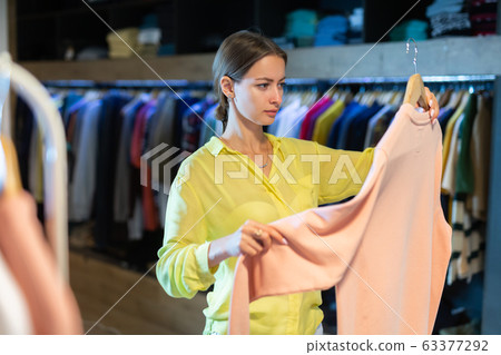 Portrait happy woman choosing new clothes on hangers Portrait happy woman choosing new clothes on hangers 63377292