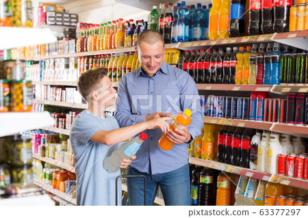 male and teen son buying sweet beverages male and teen son buying sweet beverages 63377297