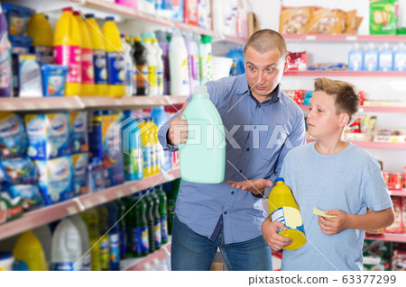 Family of father with son choosing household chemicals with shopping list Family of father with son choosing household chemicals with shopping list 63377299