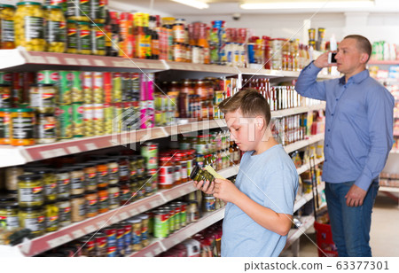Ordinary boy choosing products on shopping list Ordinary boy choosing products on shopping list 63377301