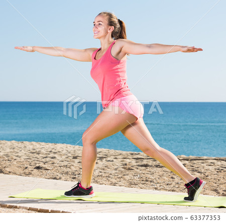cheerful young female exercising on exercise mat outdoor cheerful young female exercising on exercise mat outdoor 63377353