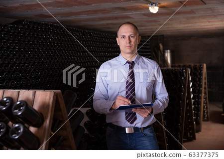 Winemaker with clipboard in wine cellar Winemaker with clipboard in wine cellar 63377375