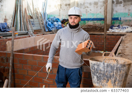 Builder working with red brick Builder working with red brick 63377403