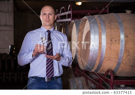 Winemaker inviting to wine degustation Winemaker inviting to wine degustation 63377415