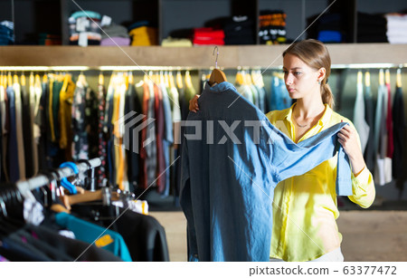 Fashionable woman buys denim shirt 63377472