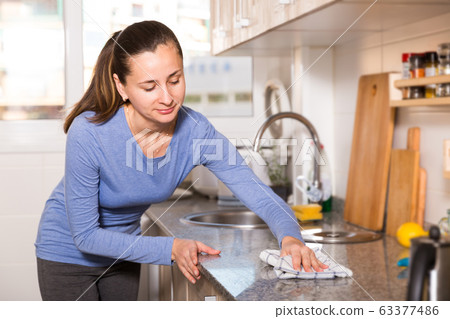 Smiling woman is cleaning surface on the kitchen at the home 63377486