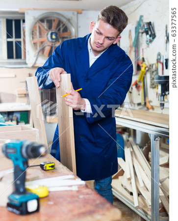Guy carpenter adjusting chipboard at workshop 63377565