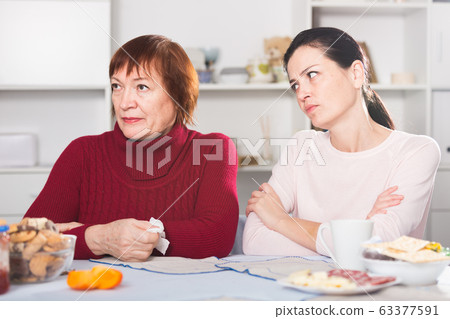 Unhappy adult female quarrel with daughter at table Unhappy adult female quarrel with daughter at table 63377591