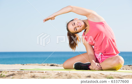 vigorous young woman exercising on exercise mat outdoor 63377600