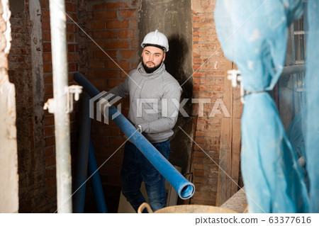 Young man assembling plastic pipes 63377616