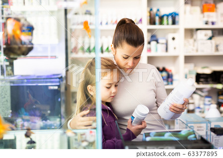 Woman with daughter searching aquarium supplies in shop 63377895