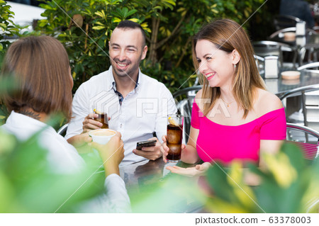 Man with two young women are talking about life and lunching Man with two young women are talking about life and lunching 63378003