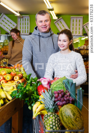 Girl with father choosing pineapple Girl with father choosing pineapple 63378238