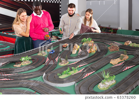 Two teams from couples play slot car racing game Two teams from couples play slot car racing game 63378260