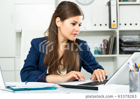 Successful adult business woman using laptop at workplace Successful adult business woman using laptop at workplace 63378263