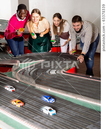 Portrait of smiling males and females posing with slot car racing game Portrait of smiling males and females posing with slot car racing game 63378339