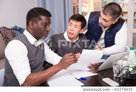 Three men are looking on documents and talking about it together Three men are looking on documents and talking about it together 63378635