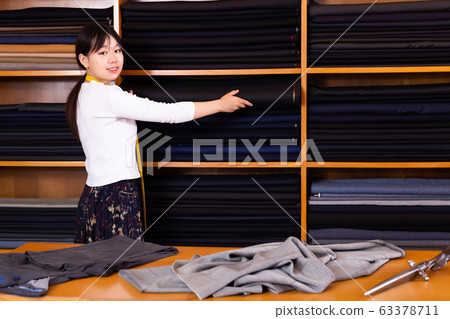Saleswoman offering cloth in textile shop Saleswoman offering cloth in textile shop 63378711
