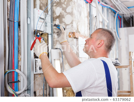 Builder engaged in electrical installation work Builder engaged in electrical installation work 63379062