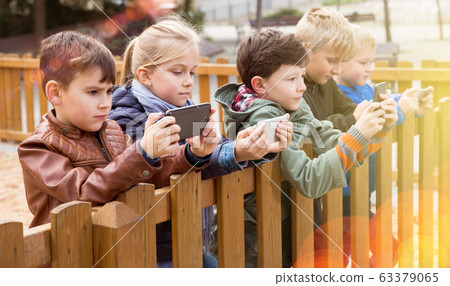 Five kidsare chatting on their smartphone Five kidsare chatting on their smartphone 63379065