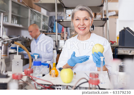Happy female biochemist showing apple Happy female biochemist showing apple 63379230