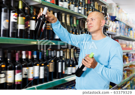 Portrait of happy customer selecting wine Portrait of happy customer selecting wine 63379329