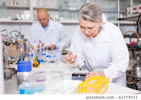 Female chemist mixing chemical agents Female chemist mixing chemical agents 63379331