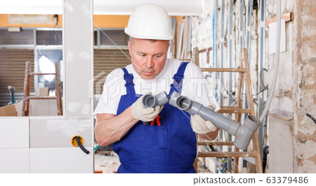 Plumber assembling plastic pipes Plumber assembling plastic pipes 63379486