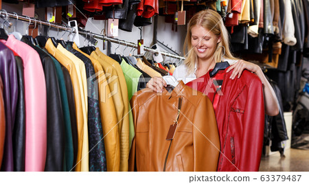 blonde choosing leather jacket on racks blonde choosing leather jacket on racks 63379487