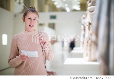 woman with guidebook standing in museum woman with guidebook standing in museum 63379548