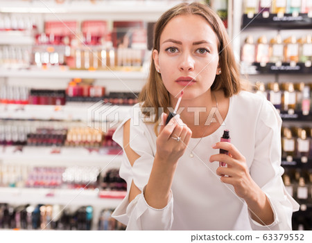 Girl buying lipstick in makeup store Girl buying lipstick in makeup store 63379552