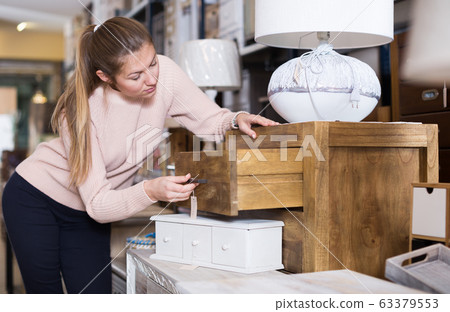 woman consumer choosing chest of drawers 63379553