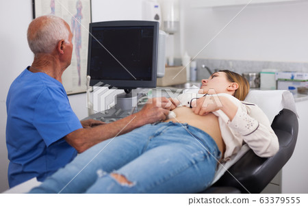Elderly male sonographer examining woman Elderly male sonographer examining woman 63379555